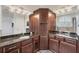 Bathroom featuring dual vanities with granite countertops, dark wood cabinetry, and an ornate mirror at 8228 Villa Grande Ct, Sarasota, FL 34243