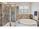 Elegant bathroom featuring a separate glass-enclosed shower and luxurious soaking tub under a window at 8228 Villa Grande Ct, Sarasota, FL 34243