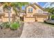 Inviting townhome exterior featuring a multi-car garage, brick driveway, and tropical landscaping including palms at 8228 Villa Grande Ct, Sarasota, FL 34243