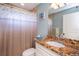 Well-lit bathroom featuring a granite vanity top, seashell shower curtain, and neutral paint at 9325 Crugar Ter, Englewood, FL 34224