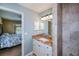 Bright bathroom with granite counters, white vanity, tile shower, and view to the bedroom at 9325 Crugar Ter, Englewood, FL 34224