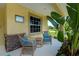 Cozy front porch featuring wicker seating and tropical plants, creating a relaxing outdoor space at 9325 Crugar Ter, Englewood, FL 34224