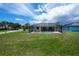 Backyard view of a screened-in pool, surrounded by a green lawn and blue skies at 9325 Crugar Ter, Englewood, FL 34224