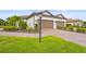 Villa featuring two-car garage, brick driveway, palm trees and decorative landscaping and lawn at 10258 Morning Mist Ln, Sarasota, FL 34241
