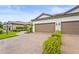 Villa exterior featuring a two-car garage, brick driveway, and meticulously maintained decorative plants at 10258 Morning Mist Ln, Sarasota, FL 34241