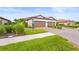 Villa exterior featuring a two-car garage, brick driveway, manicured lawn, and decorative plants at 10258 Morning Mist Ln, Sarasota, FL 34241