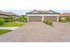 Charming villa with a two-car garage, brick driveway and tile roof, complemented by neat landscaping at 10258 Morning Mist Ln, Sarasota, FL 34241