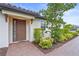 Home featuring a brown front door, brick pathway, lush landscaping, and a stucco exterior at 10258 Morning Mist Ln, Sarasota, FL 34241