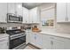 Well-lit kitchen featuring stainless steel appliances, white cabinets, and modern finishes at 10258 Morning Mist Ln, Sarasota, FL 34241