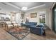 Bright living room featuring a large blue sofa, modern light fixture, and access to the kitchen area at 10258 Morning Mist Ln, Sarasota, FL 34241