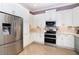 Well-lit kitchen with stainless steel refrigerator, white cabinets, and granite countertops at 10487 Coquina Ct, Placida, FL 33946