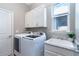 Laundry room featuring a front-load washer/dryer, window, sink, cabinets, and neutral paint at 10487 Coquina Ct, Placida, FL 33946