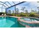 Sparkling pool and spa with screen enclosure, surrounded by lush landscaping and a stone patio at 10487 Coquina Ct, Placida, FL 33946