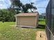 View of tan shed in back yard of property with a brown roof and white rain gutters at 11029 Vanessa Ave, Englewood, FL 34224