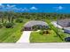 Aerial view of a home with a well-kept lawn, mature trees, and an attached two-car garage at 1119 Boundary Blvd, Rotonda West, FL 33947