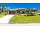 Single story home with lush green lawn, mature palm trees, and beautiful front facade at 1119 Boundary Blvd, Rotonda West, FL 33947