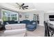 Open-concept living room featuring modern ceiling fan, sliding glass doors, and comfortable blue sofa at 1119 Boundary Blvd, Rotonda West, FL 33947