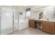 Bright bathroom with soaking tub, glass enclosed shower, dual sinks, and natural wood cabinets at 117 Abercrombie Ave, Englewood, FL 34223