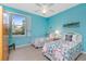 Comfortable bedroom with two twin beds, colorful decor, ceiling fan, and bright blue walls at 117 Abercrombie Ave, Englewood, FL 34223