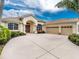 Elegant home featuring a well-manicured lawn, an arched entryway, and a spacious three-car garage at 117 Abercrombie Ave, Englewood, FL 34223