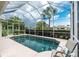 Relaxing screened-in pool area with comfortable seating and lush tropical landscaping at 117 Abercrombie Ave, Englewood, FL 34223