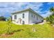 Side and rear view of home, showing lush lawn, utility hookups, and sidewalk to backyard at 123 Ferdon Cir, Port Charlotte, FL 33954