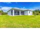 Screened-in back porch extends from home, with lush grass and blue skies above at 123 Ferdon Cir, Port Charlotte, FL 33954