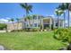 This two-story home features a metal roof, three-car garage, lush lawn, and manicured landscaping at 12438 Prather Ave, Port Charlotte, FL 33981