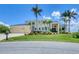Two-story home with a metal roof, three-car garage, palms, and lush landscaping at 12438 Prather Ave, Port Charlotte, FL 33981