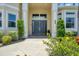 Elegant entryway features double doors, stone columns, mature landscaping, and stone pathway at 12438 Prather Ave, Port Charlotte, FL 33981