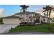 Attractive two-story home featuring a 3-car garage, well-manicured lawn, and lush landscaping at 12438 Prather Ave, Port Charlotte, FL 33981