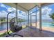 A waterfront screened patio offers a hanging chair, tile floors, and tranquil views of the adjacent waterway at 12438 Prather Ave, Port Charlotte, FL 33981