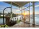Relaxing screened-in porch with hanging chair, pool access, and waterfront views at sunset at 12438 Prather Ave, Port Charlotte, FL 33981