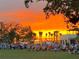 Lawn filled with residents enjoying an outdoor event beneath a vibrant orange sunset at 12550 Galapagos Ct # 104, Venice, FL 34293