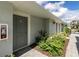 Exterior view of the condo entrance with gray door, green plants, and brick walkway at 12550 Galapagos Ct # 104, Venice, FL 34293