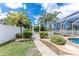 Landscaped backyard with a charming white picket fence, decorative gate, lush green lawn, and access to the screened pool area at 127 Jennifer Dr, Rotonda West, FL 33947