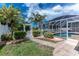 Serene backyard showcasing a well-manicured lawn, white picket fence, decorative gate, and a glimpse of the screened pool area at 127 Jennifer Dr, Rotonda West, FL 33947