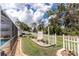 Lush backyard showcasing a well-manicured lawn, stone pathway, access to the screened pool, and a white picket fence at 127 Jennifer Dr, Rotonda West, FL 33947