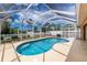 An enclosed pool area features a freeform pool, white screen enclosure, and surrounding patio, perfect for relaxation and recreation at 127 Jennifer Dr, Rotonda West, FL 33947