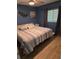 Cozy bedroom featuring a blue and white striped bedspread, hardwood floors, and natural light at 1401 S Mccall Rd # 101, Englewood, FL 34223