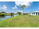 Lush green lawn with a canal view, dotted with mature palm trees creating a relaxing backyard oasis at 15 Bunker Pl, Rotonda West, FL 33947