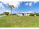 Waterfront backyard with a lush green lawn and a mature palm tree creating a private oasis at 15 Bunker Pl, Rotonda West, FL 33947