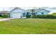 Charming blue single-story home featuring a well-manicured lawn and tropical landscaping at 15 Bunker Pl, Rotonda West, FL 33947