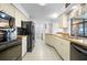 Galley kitchen with black appliances, white cabinets and pantry access at 15 Oakland Hills Pl, Rotonda West, FL 33947