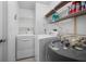 Bright laundry room featuring a modern washer, dryer, water heater, and ample shelving for organized storage at 15 Oakland Hills Pl, Rotonda West, FL 33947