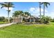 Beautiful home with tropical landscaping featuring mature palms, colorful flowers, and a pristine lawn at 15521 Lakeland Cir, Port Charlotte, FL 33981