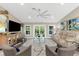 Cozy living room featuring a large screen TV, sofa, comfortable seating, and an outdoor view at 15521 Lakeland Cir, Port Charlotte, FL 33981