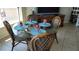 Dining room with a glass table set for four, complemented by stylish rattan chairs and tableware at 1760 Gulf Blvd # 511, Englewood, FL 34223
