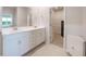Bright bathroom with double sinks, white cabinets, and an ensuite walk-in closet at 17921 Grand Prosperity Dr, Venice, FL 34293
