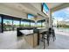 Outdoor bar area with sleek countertops, bar stools, and televisions, perfect for entertaining by the pool at 17921 Grand Prosperity Dr, Venice, FL 34293